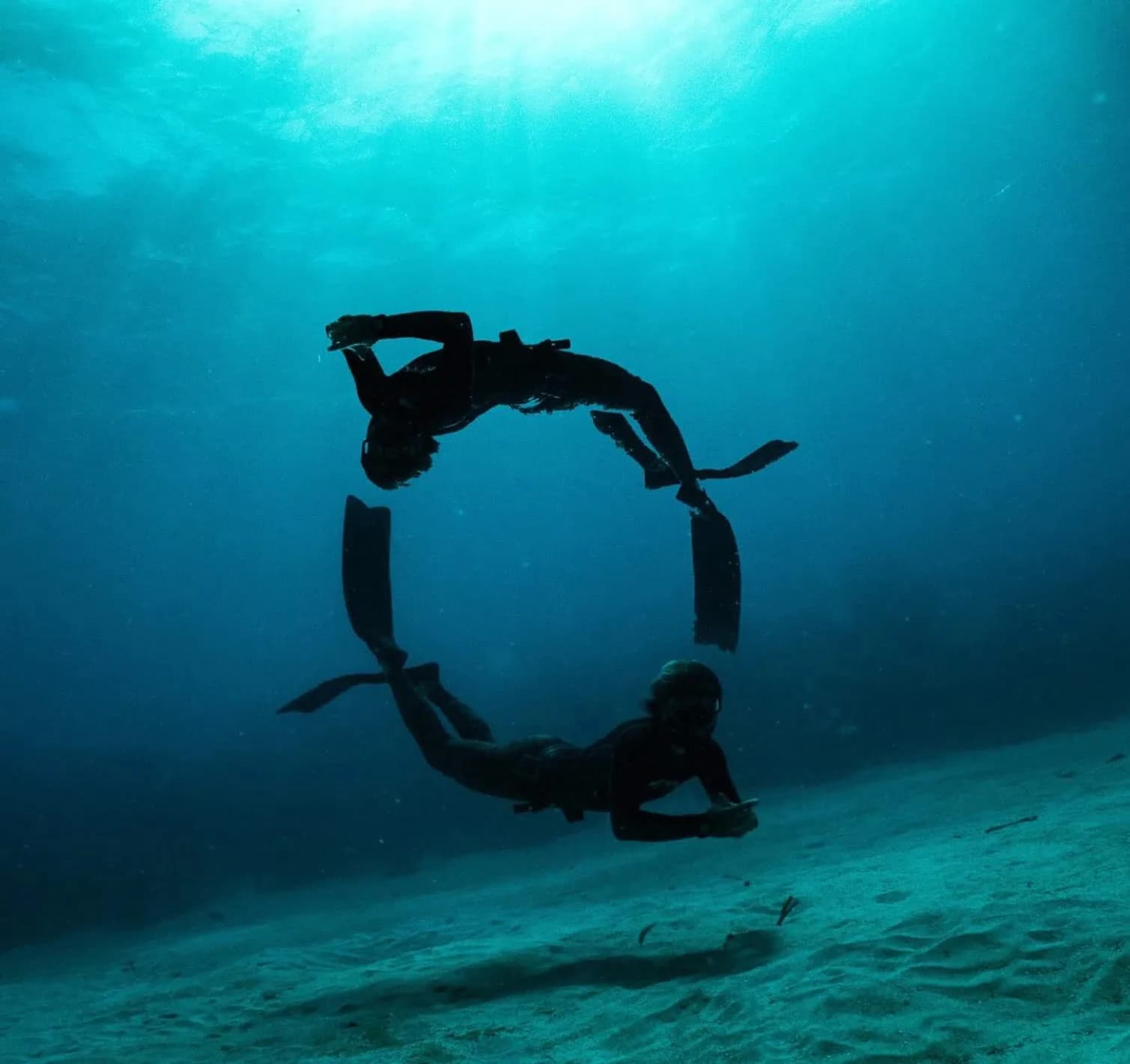 A freediver in turquoise water above the reef