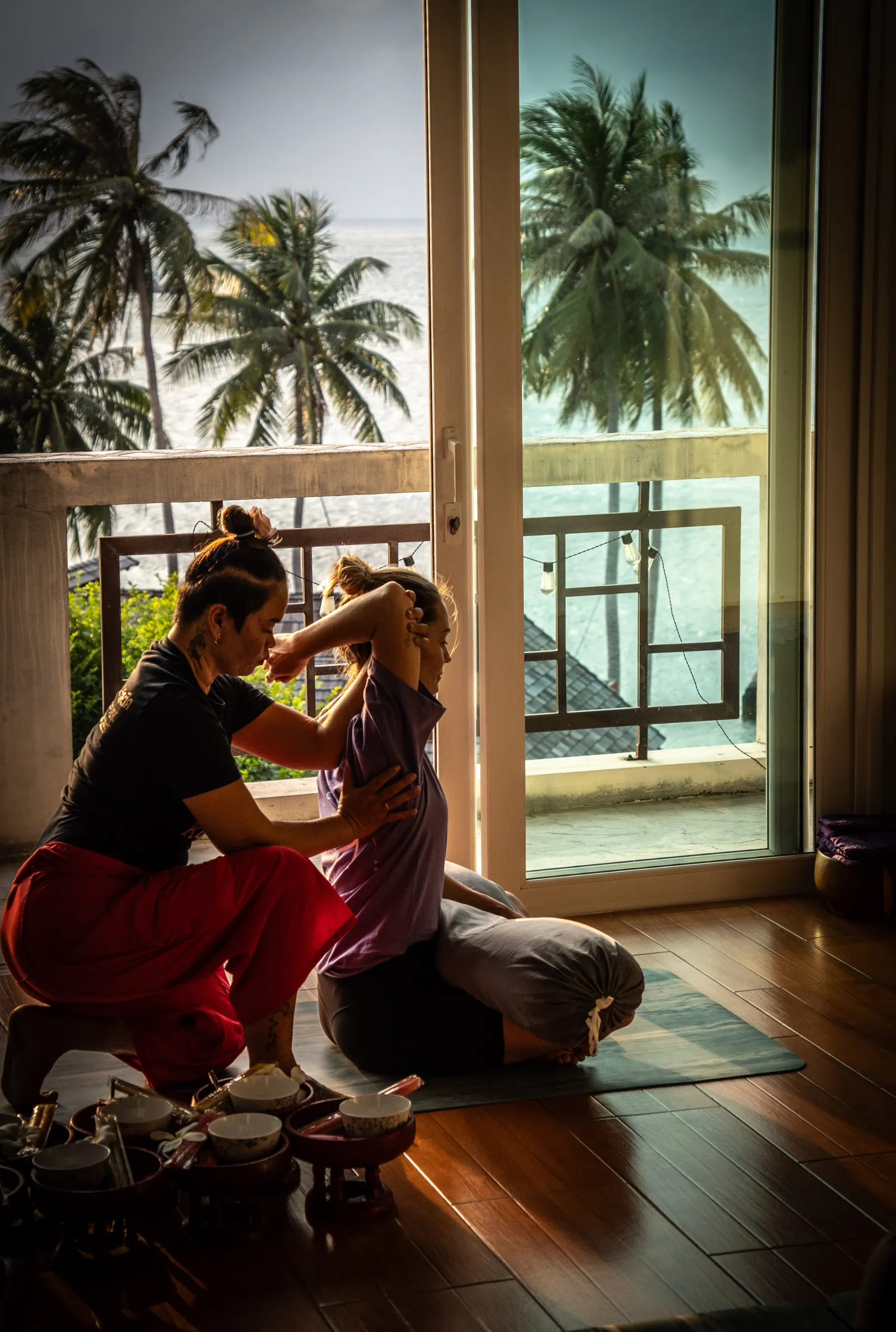 Darunee Gor giving a seated Thai Massage stretch by the window of the sea-view shala