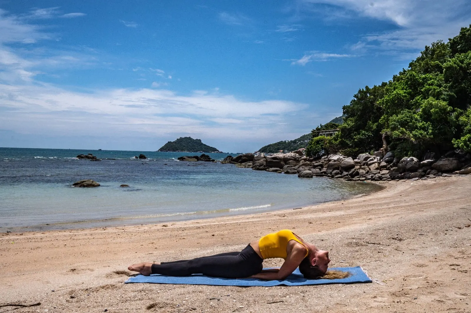 Fish Pose (Matsyasana) practised on a yoga mat on the beach