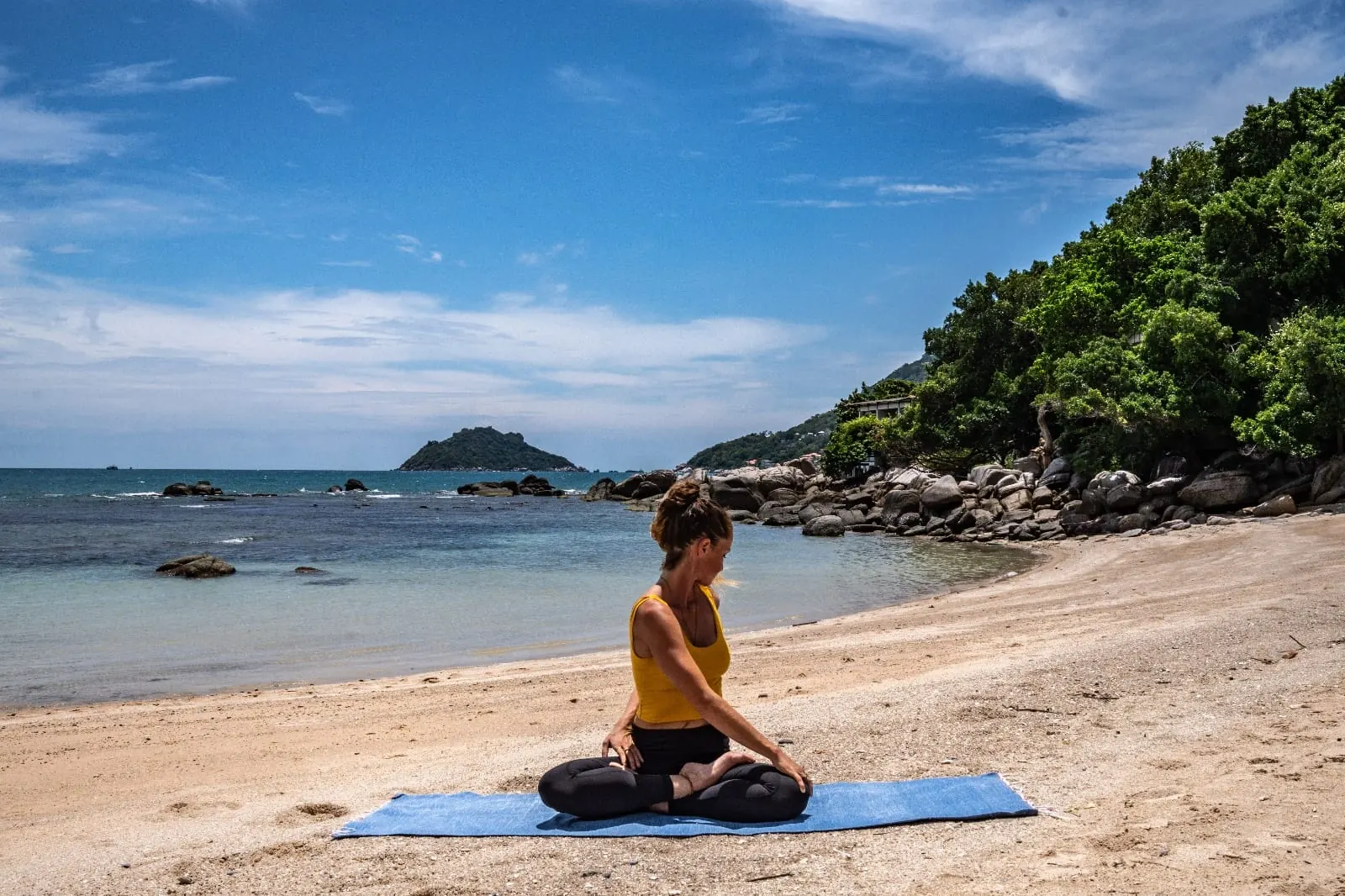 A seated twist practised cross-legged on a beach yoga mat