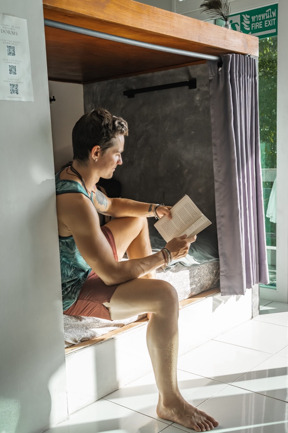A guest reading in a curtained bunk in the wellness dorm