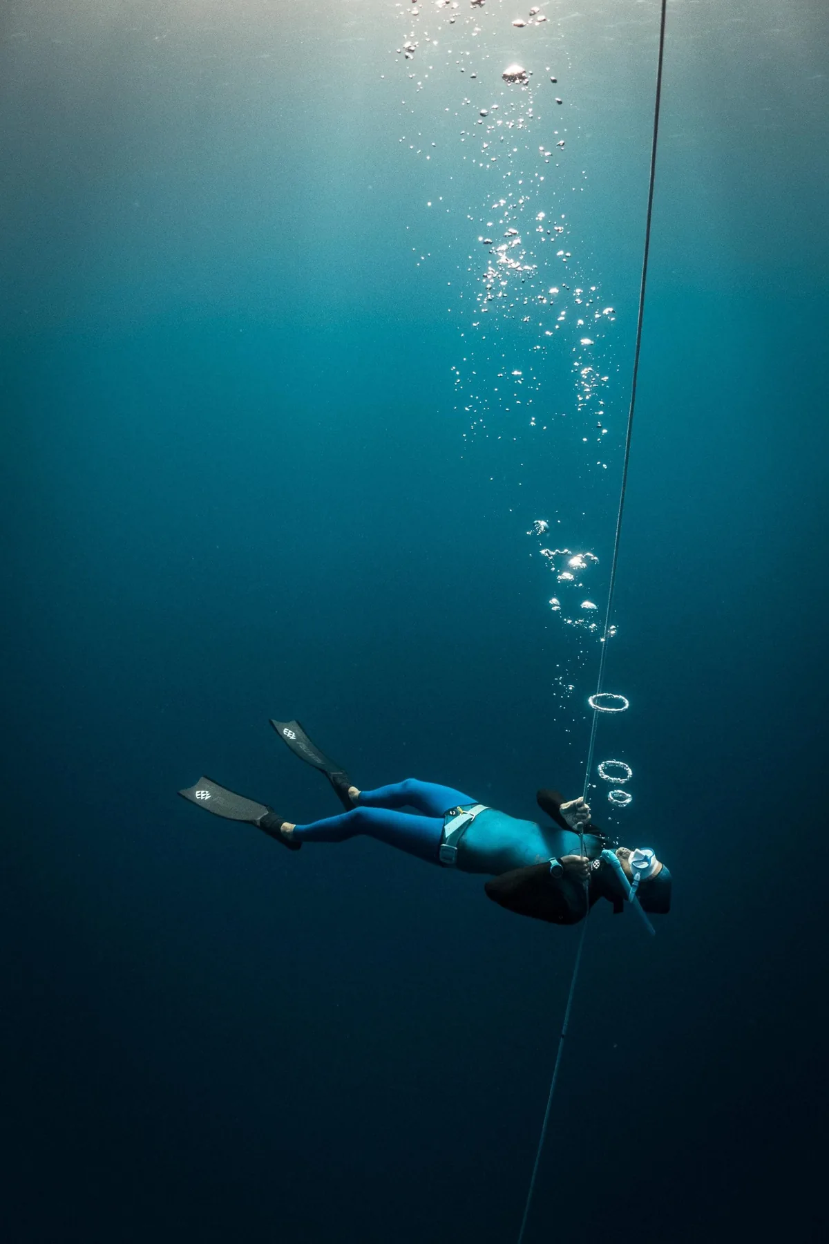 A freediver descending head-first along the line