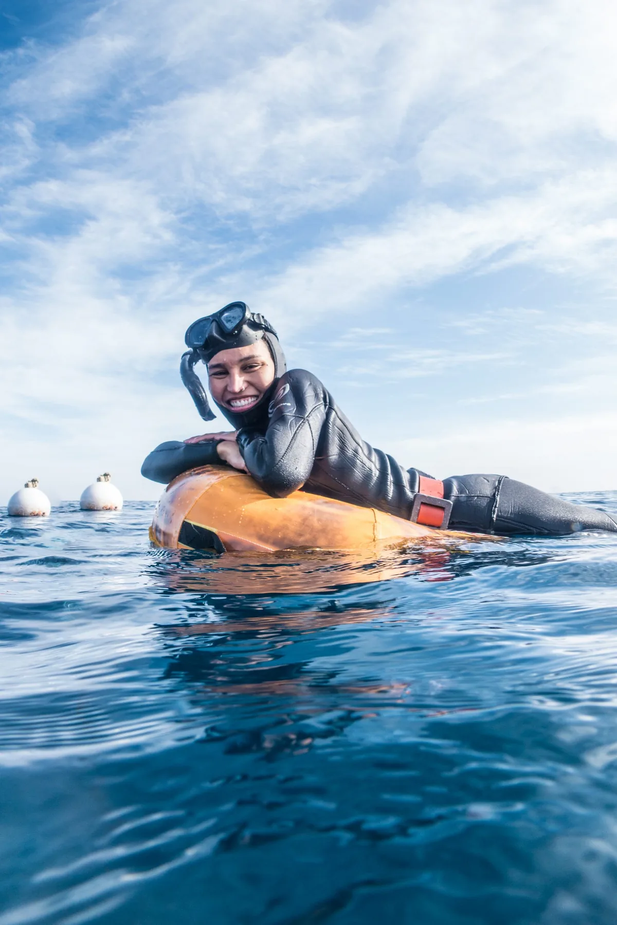 A freediver resting at the surface beside the buoy
