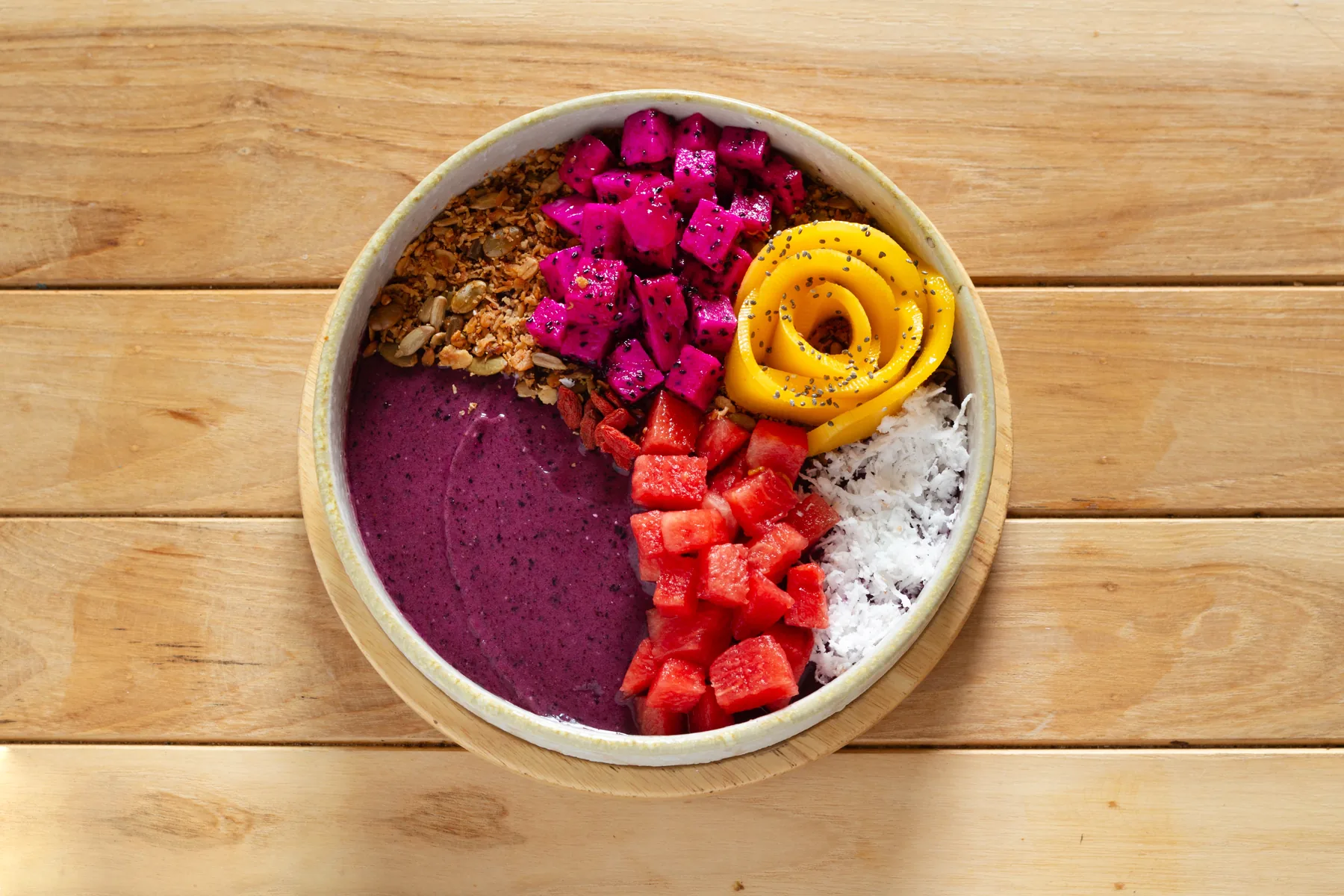 A fruit and granola bowl on a wooden table