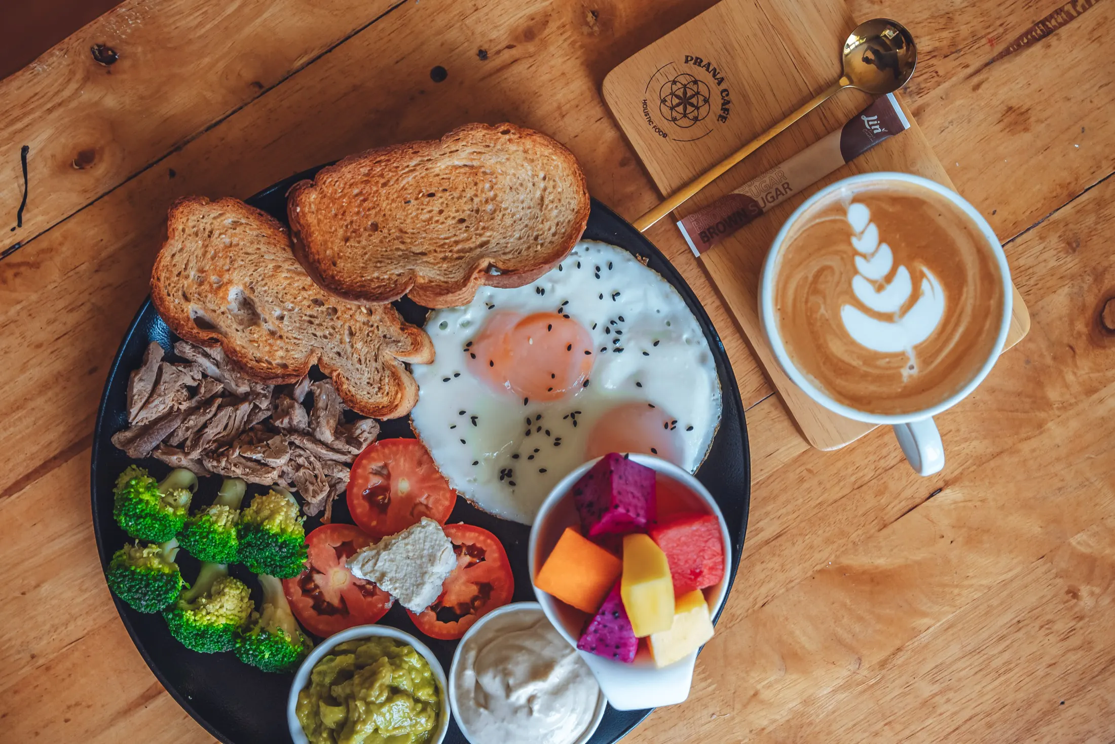 Breakfast plate with eggs, toast and fruit, and a latte at Prana Café