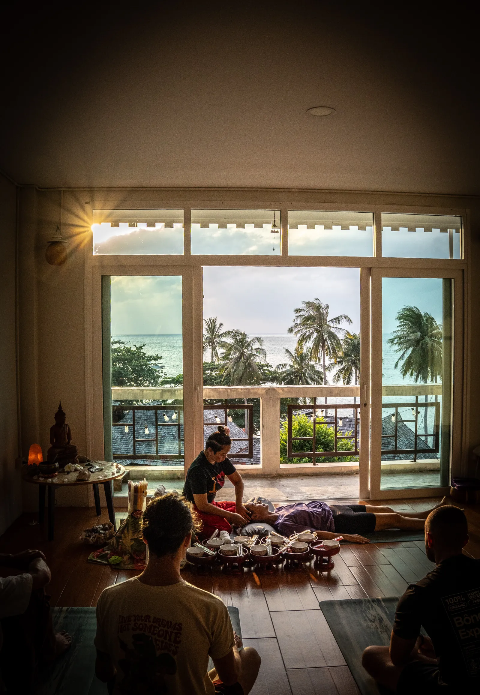 A Thai Massage demonstration in the shala at sunset, palm trees and sea through the open windows